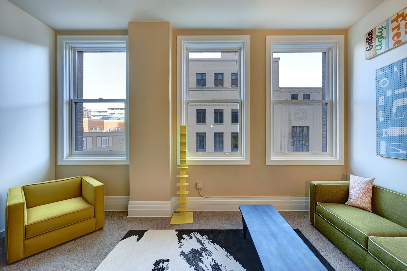 Living room with historic windows and downtown Des Moines views at The Fleming Building